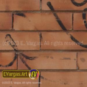 closeup of a reddish brick wall with graffitti on it